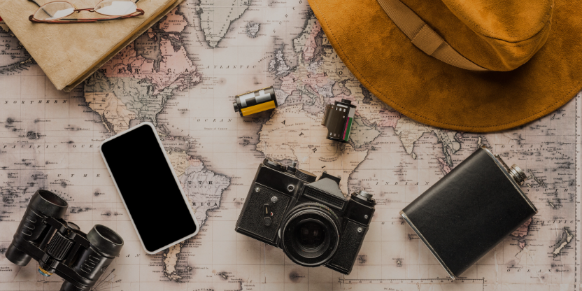 Eco-conscious travel gear flat lay with vintage camera, map, phone, and explorer hat for sustainable travel planning