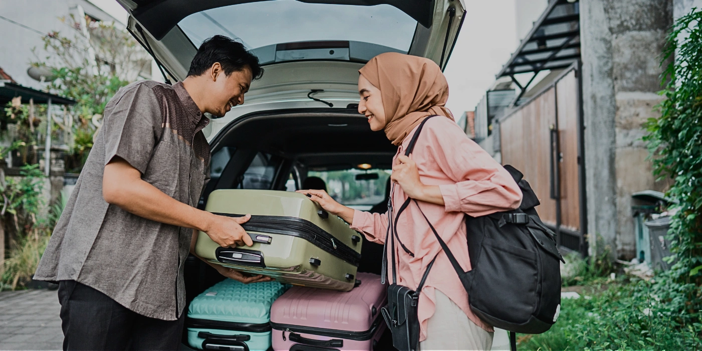 Couple loading their luggage into the trunk of a car, preparing for a scenic drive to Kinabatangan River in Sabah, Borneo