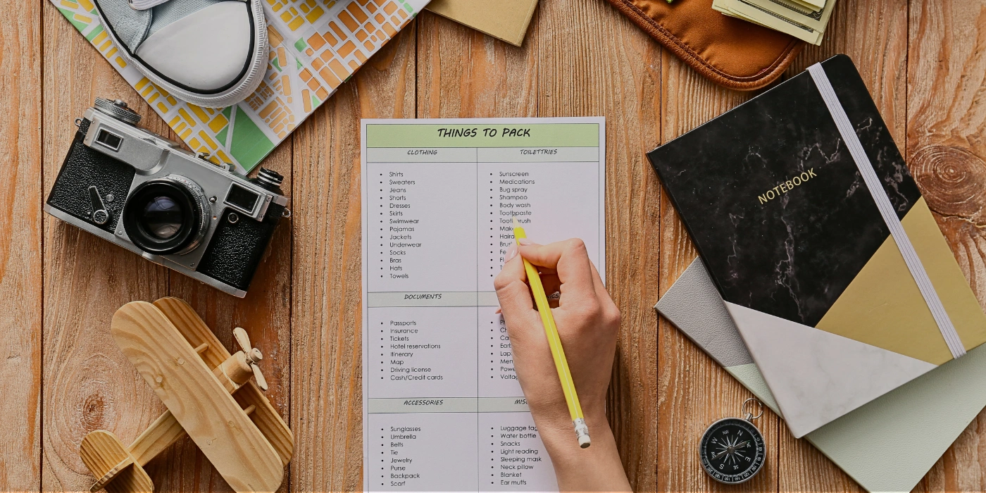 Travel packing checklist with items like insect repellent, quick-dry clothes, headlamp, and binoculars written on a notepad for a Kinabatangan River trip