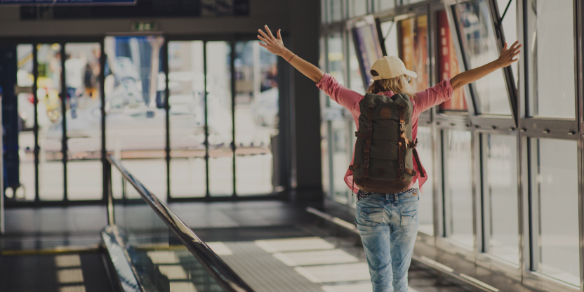 Excited female traveler with backpack walking through airport ready for eco-adventure