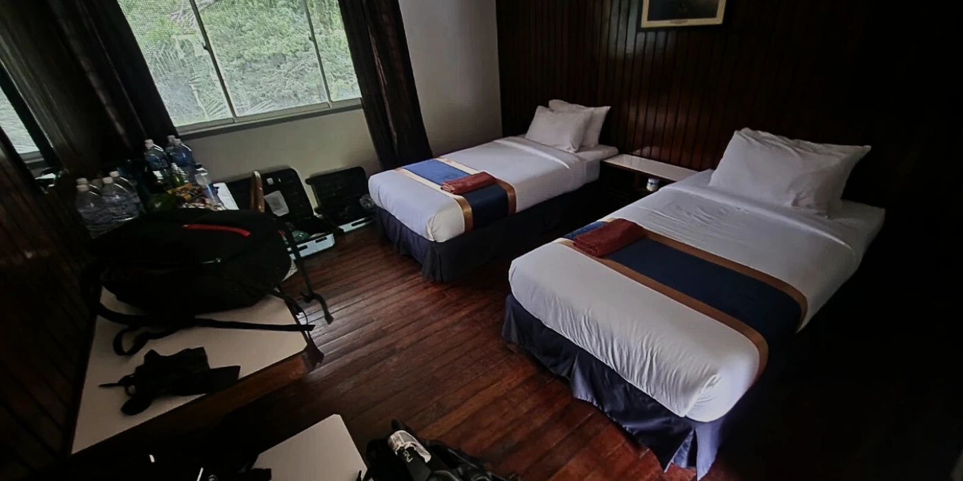 Simple accommodation at DVFC featuring twin beds, wall fan and minimal decor