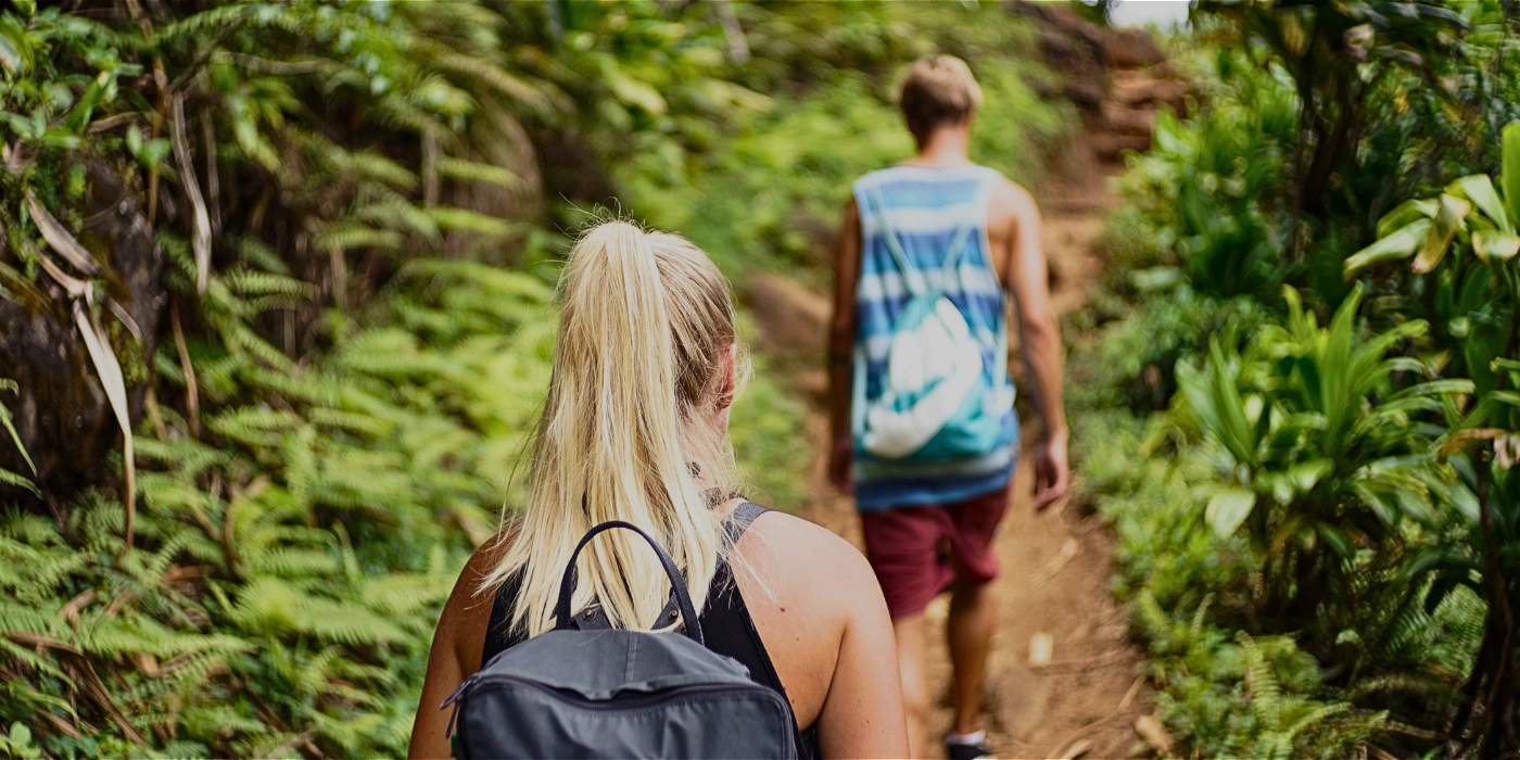 A couple trekking along a lush jungle trail in Taman Negara National Park, Malaysia