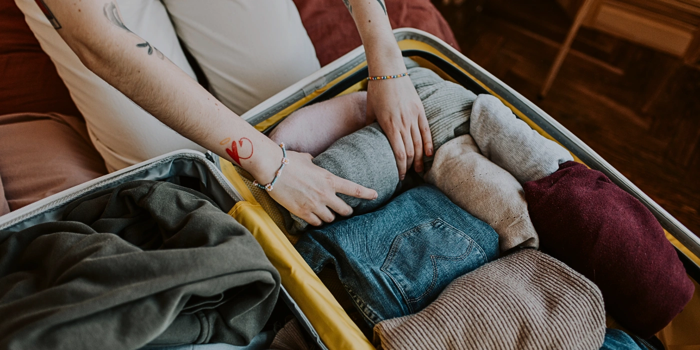 Female traveler packing clothes into a suitcase, preparing for a tropical trip or eco-tour in Southeast Asia