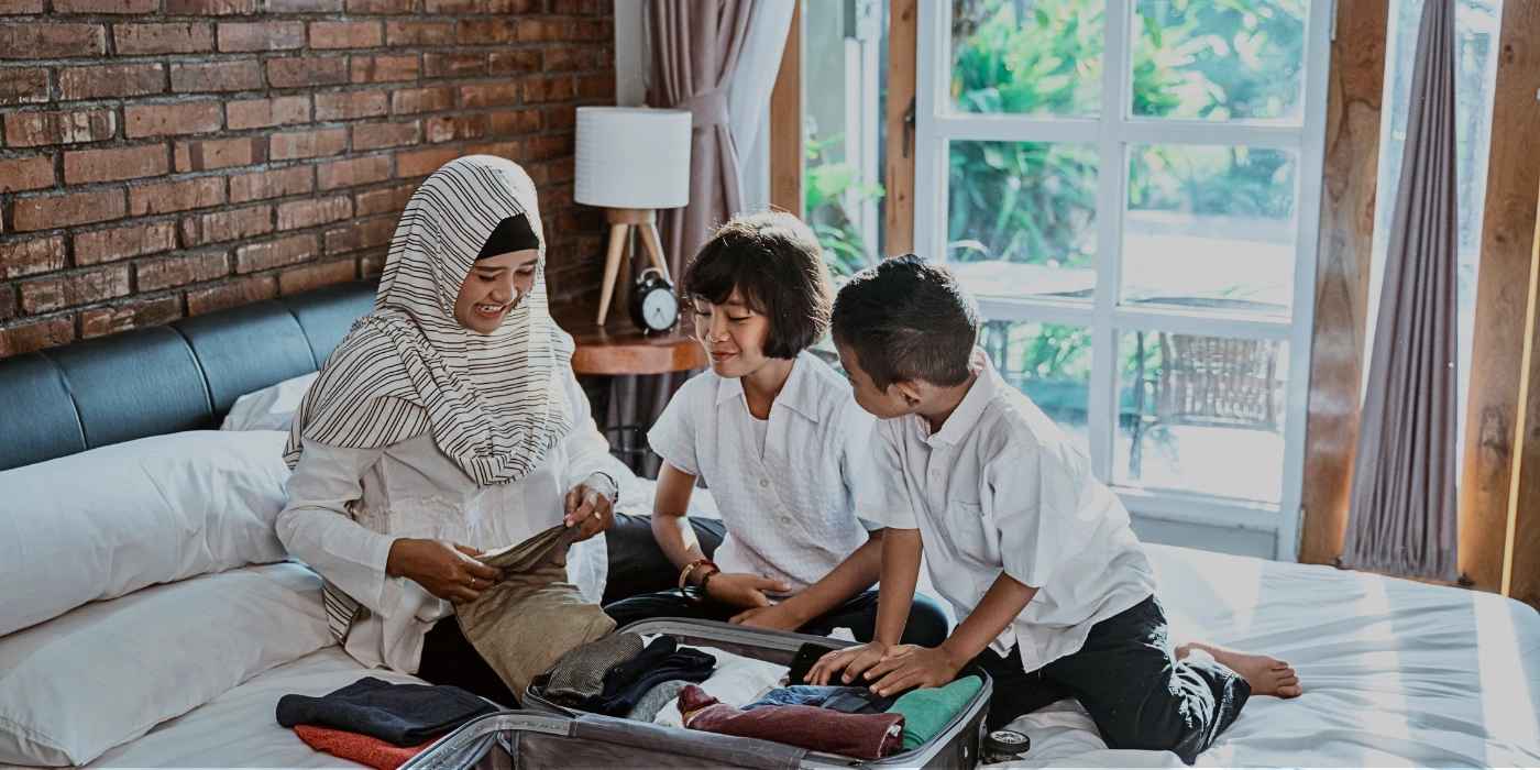 A mother and her children packing clothes and travel essentials for a family trip to Sepilok