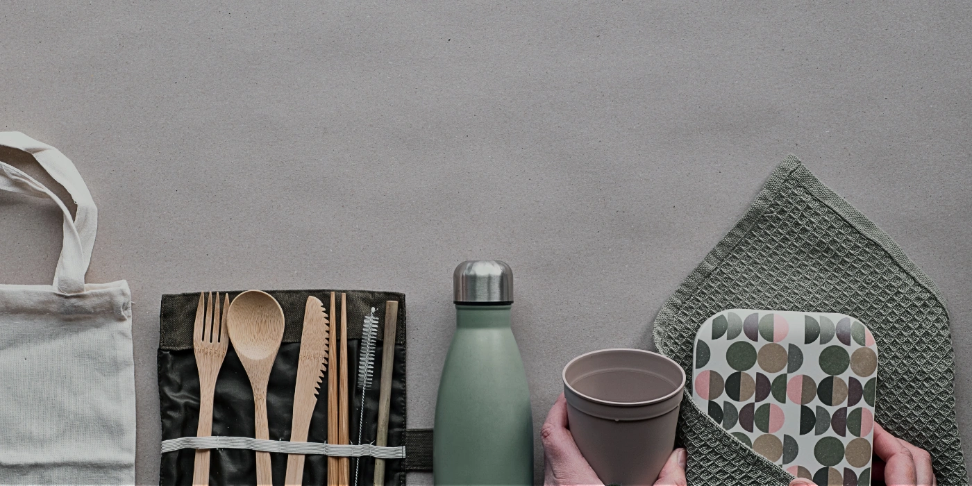 Flat lay of reusable utensils, a water bottle, and eco-bags—sustainable packing items for a trip to Taman Negara National Park, Malaysia