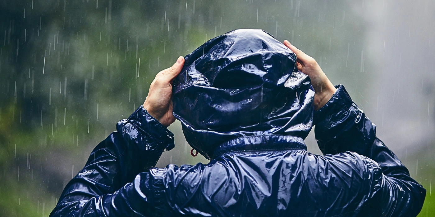 Man wearing a raincoat in the rainforest, prepared for sudden downpours in Tabin Wildlife Reserve