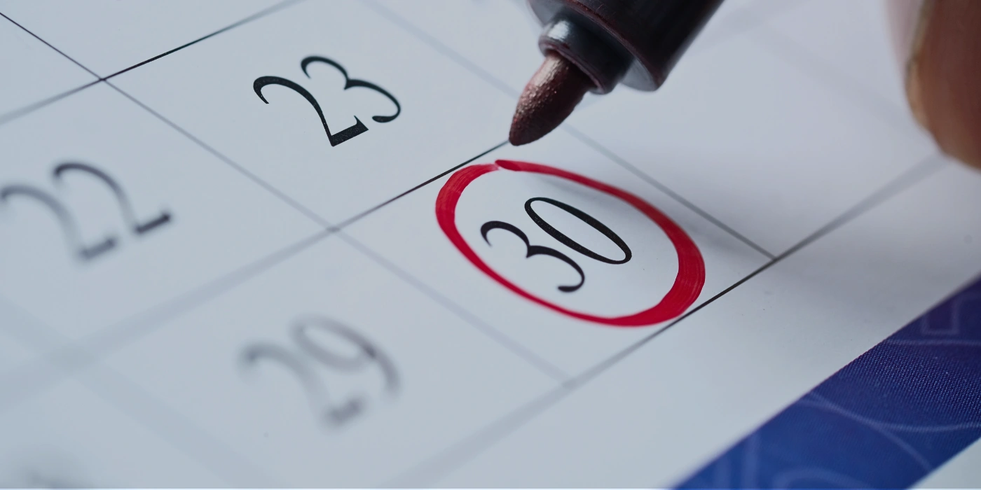 Close-up of a hand marking travel dates on a calendar to plan a night safari in Danum Valley