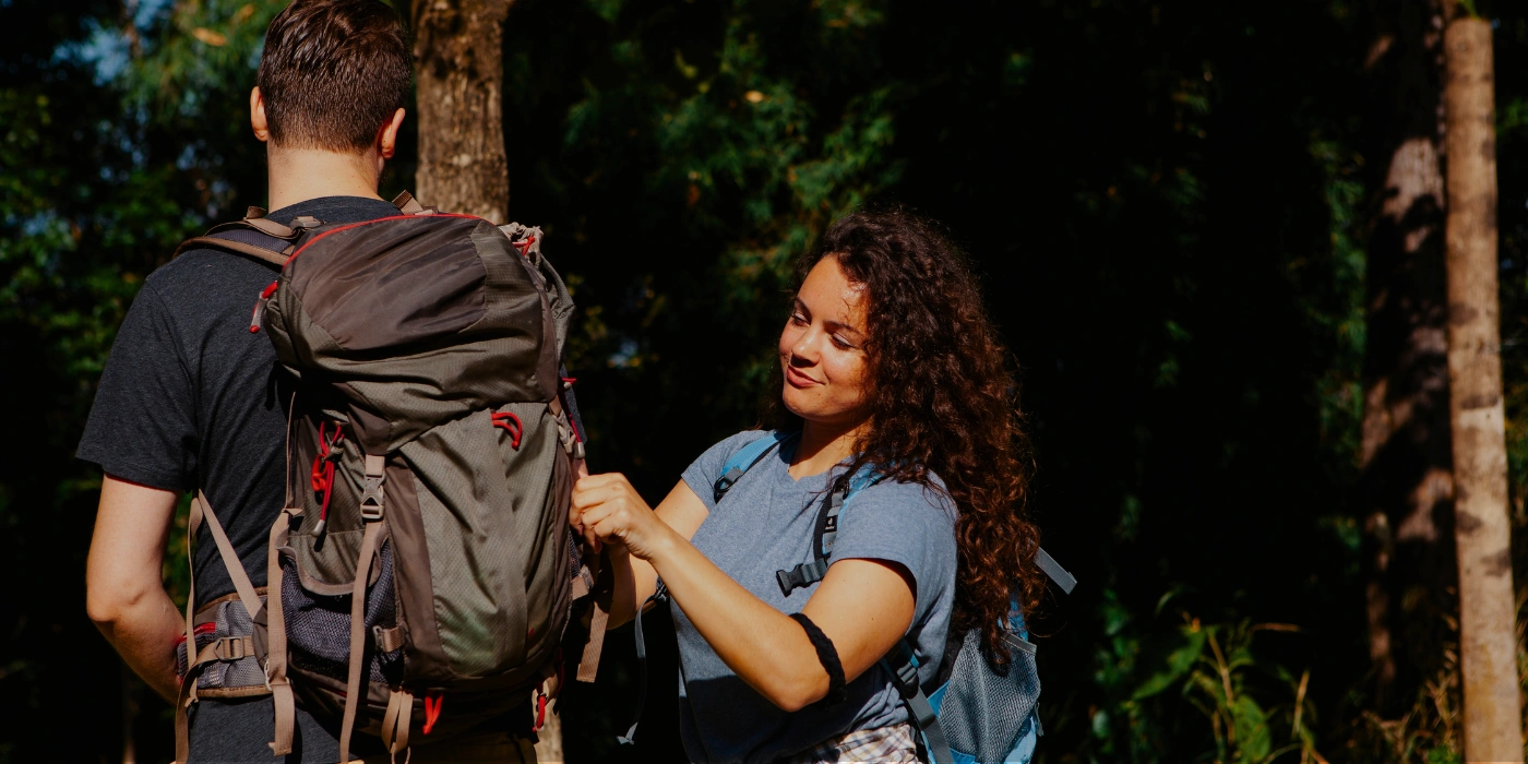 A young woman adjusting her partner's backpack straps during a jungle trek in Tabin Wildlife Reserve, Sabah- tabin is ideal for couples