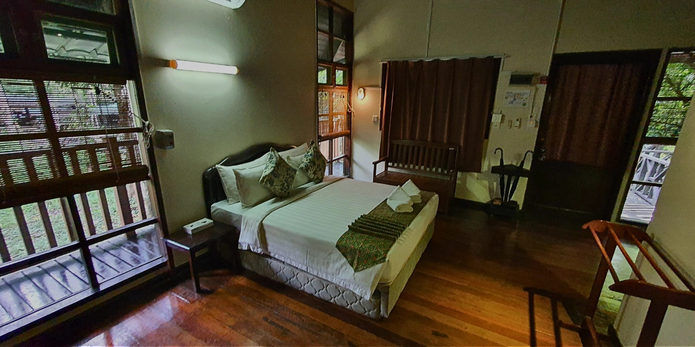 Cozy double bed in a wooden chalet at Tabin Hill Lodge, ideal for couples seeking a rainforest getaway