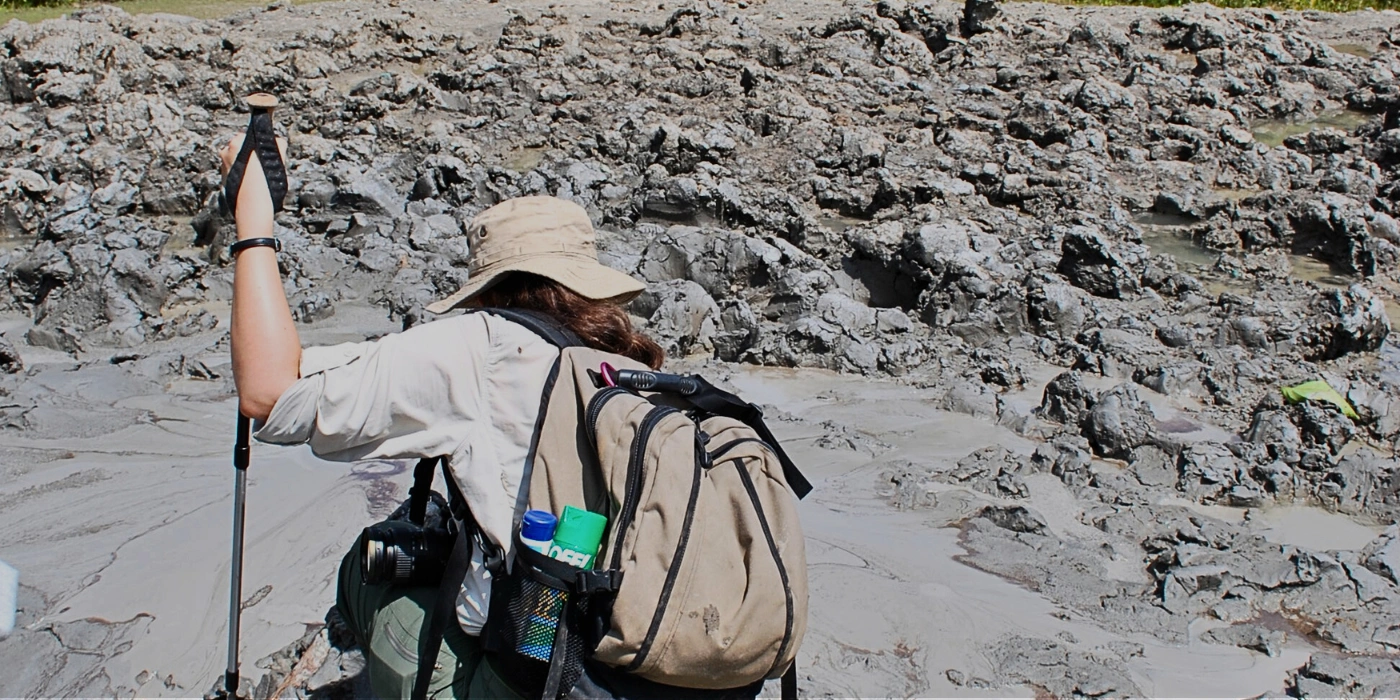 A woman closely observing and studying the surface of Tabin’s mud volcano in Sabah’s rainforest