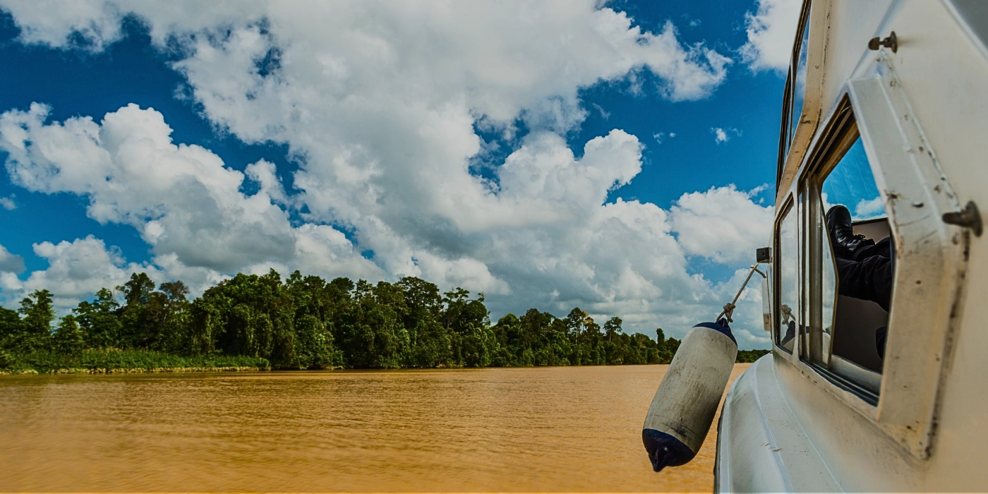 A small boat carrying tourists on a river cruise along the Kinabatangan River in Sabah, Borneo