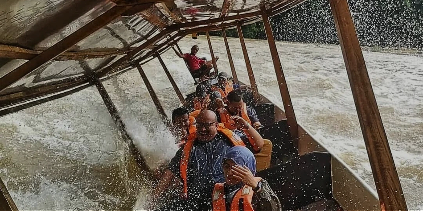 Water splashing as a longboat speeds through the river during a rapid shooting adventure in Taman Negara