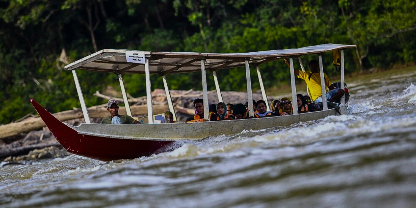 Tourists on a longboat enjoying a rapid shot the lush rainforest river of Taman Negara, Malaysia