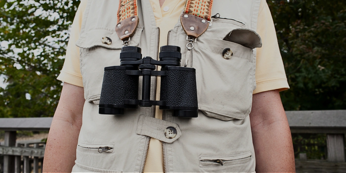 A pair of binoculars and neutral-toned clothing laid out for a birdwatching trip in Tabin Wildlife Reserve- birdwatching in Tabin